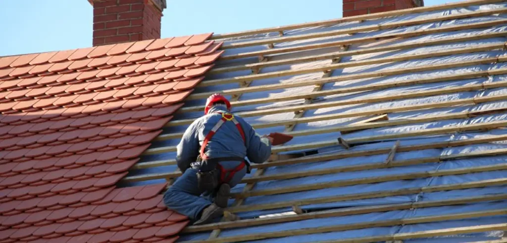 A Roofing Whangarei specialist installs terracotta tiles during a detailed re-roofing project.