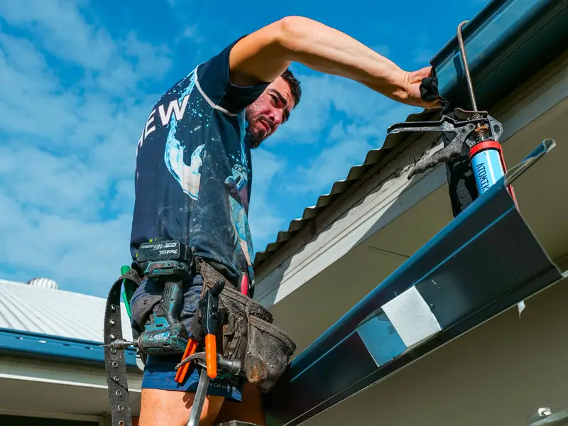 Roofing Whangarei professional applying sealant to metal gutters during Gutter and Flashing Repairs.