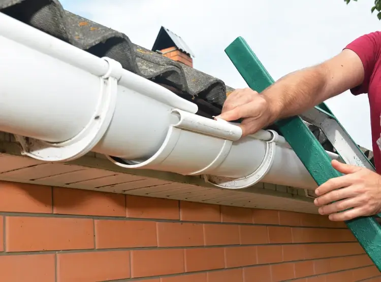 Roofing Whangarei technician inspecting and adjusting white guttering during Gutter and Flashing Repairs.