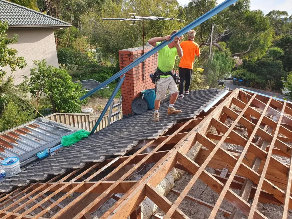 Workers from Roofing Whangarei replace old sheets with new panels in a re-roofing job.