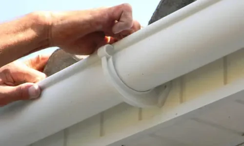 Close-up of Roofing Whangarei carrying out Gutter and Flashing Repairs on white roof gutters. Close-up of Roofing Whangarei carrying out Gutter and Flashing Repairs on white roof gutters.